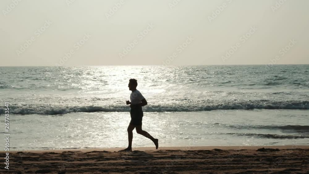 silhouette student tourist young athlete runner man with fit strong body training on beautiful Summer sunset beach sand running barefoot in sport well being and healthy lifestyle concept silhouette student tourist young athlete runner man with fit strong body training on beautiful Summer sunset beach sand running barefoot in sport well being and healthy lifestyle concept