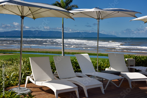 Deck chairs and umbrellas at a resort on the beach with surf