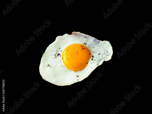 Fried egg sunny side up with pepper isolated on black background photo