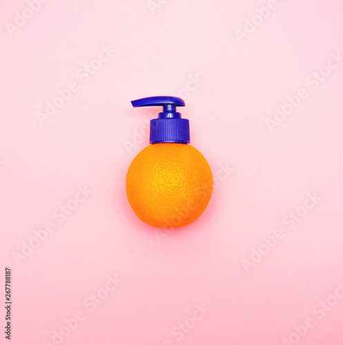 Fresh orange with dispenser on pink background
