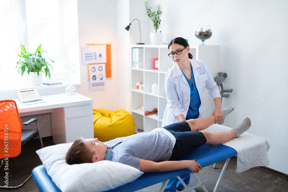 Gentle professional doctor moving around hurting leg Gentle professional doctor moving around hurting leg