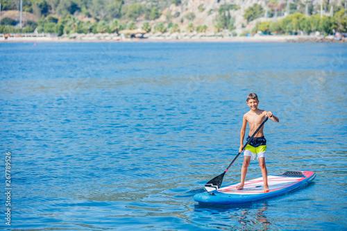 Paddle boarder. Child boy paddling on stand up paddleboard. Healthy lifestyle. Water sport, SUP surfing tour © Max Topchii