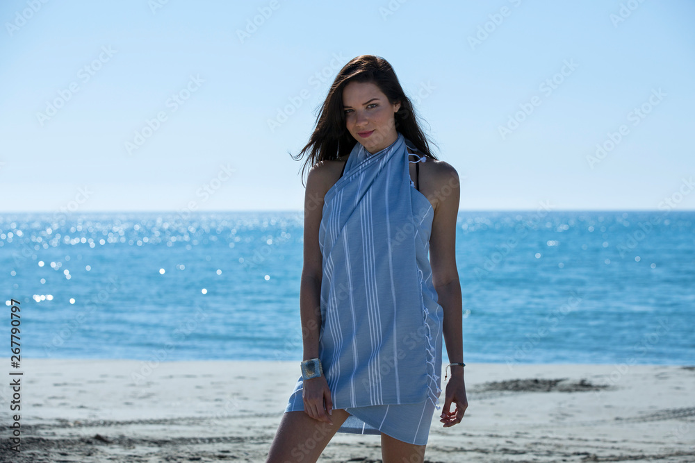 Pretty young girl wrapped in beach towel posing to the camera. Full length photo shoot and wonderful hair. Healthy, beauty and summer holiday concept. Pretty young girl wrapped in beach towel posing to the camera. Full length photo shoot and wonderful hair. Healthy, beauty and summer holiday concept.