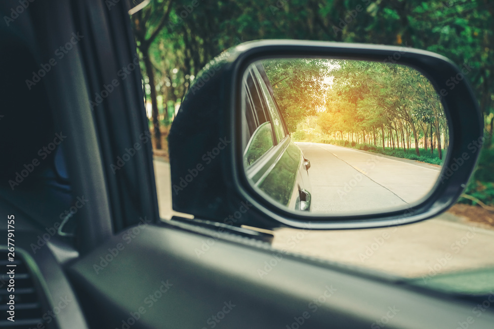 Car side mirrors with natural road travel in warm sunlight.