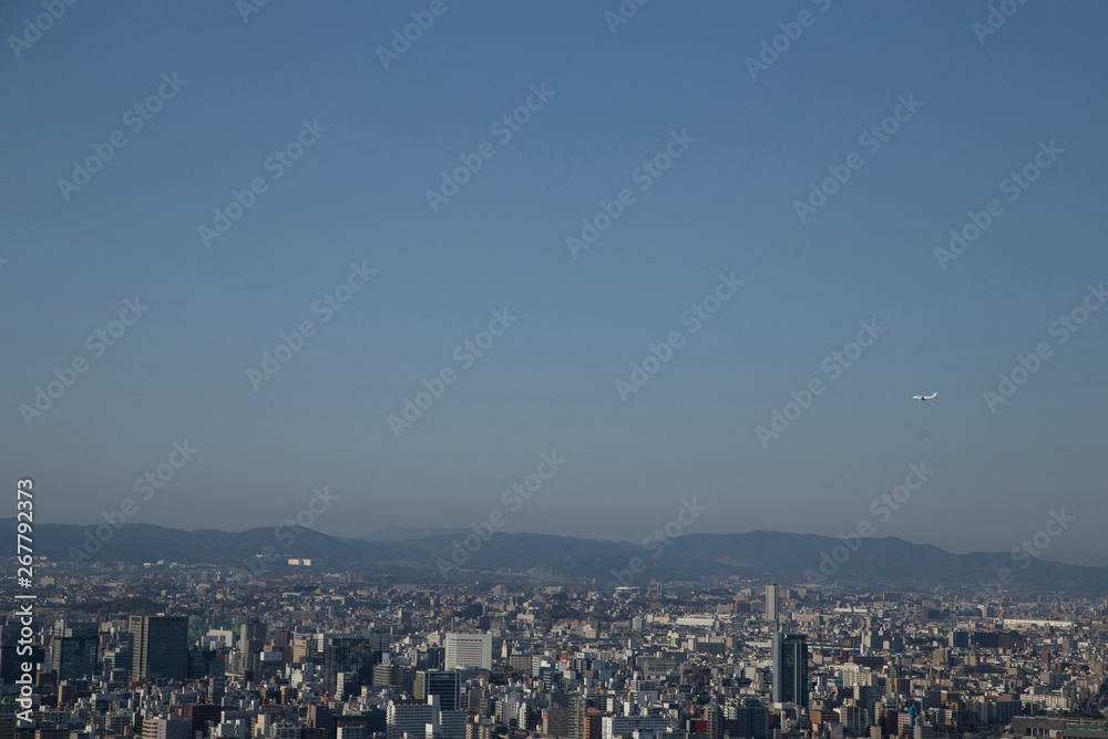 Plane and view of Osaka from the Umeda Building at sunset on a sunny day