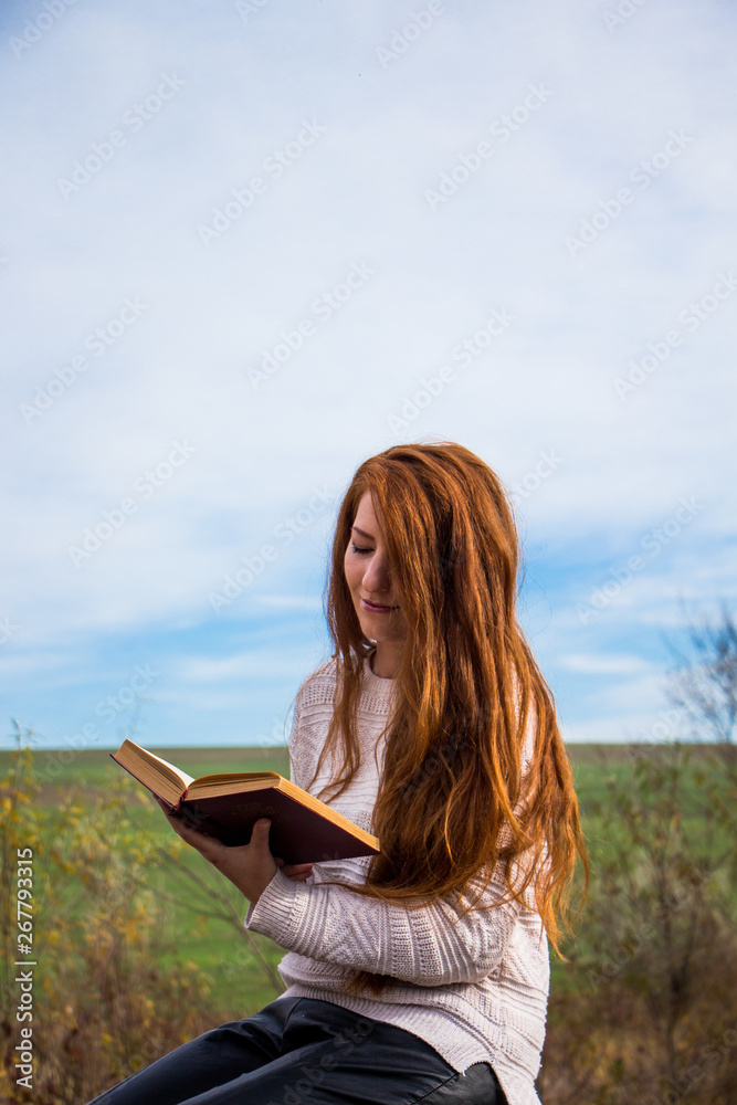 Obraz premium Young redhead woman reading a book