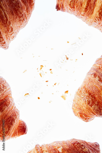 Frame of fresh homemade croissants with crumbs on a light background.