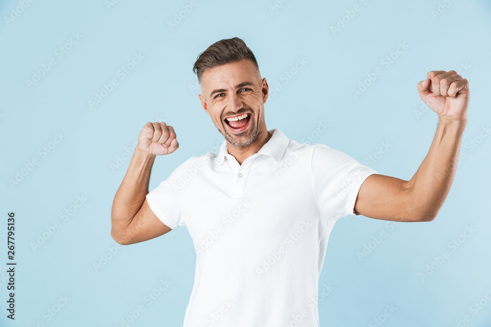 Handsome excited emotional adult man posing isolated over blue wall background dancing. Handsome excited emotional adult man posing isolated over blue wall background dancing.