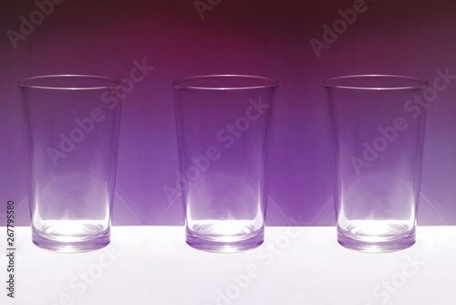 Tres basos de cristal sobre fondo purpura iluminado
