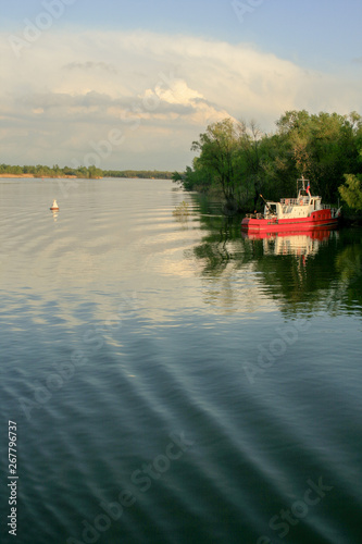 A small red and white ship near the river