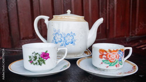 china porcelain teapot with flower pattern and white glass on the old house terrace in indonesia - asian