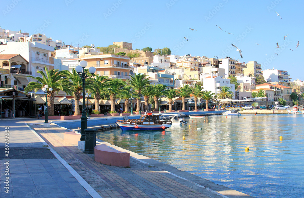 Еypical European tourist city by the sea in turquoise lagoon, reflection of houses in the blue water, seagulls flying in the clear blue sky, summer landscape, travel concept