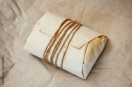 Paper wrapped parcel with hemp cord on brown background. Package for delivery. 