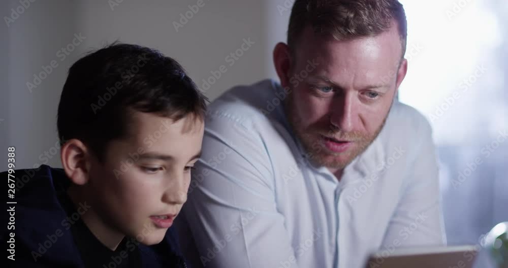 4K Father spending time with son at home, internet browsing or helping with his homework. Slow motion. 4K Father spending time with son at home, internet browsing or helping with his homework. Slow motion.