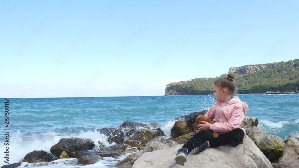 Little girl sitting on the rocks with her sweet puppy Little girl sitting on the rocks with her sweet puppy