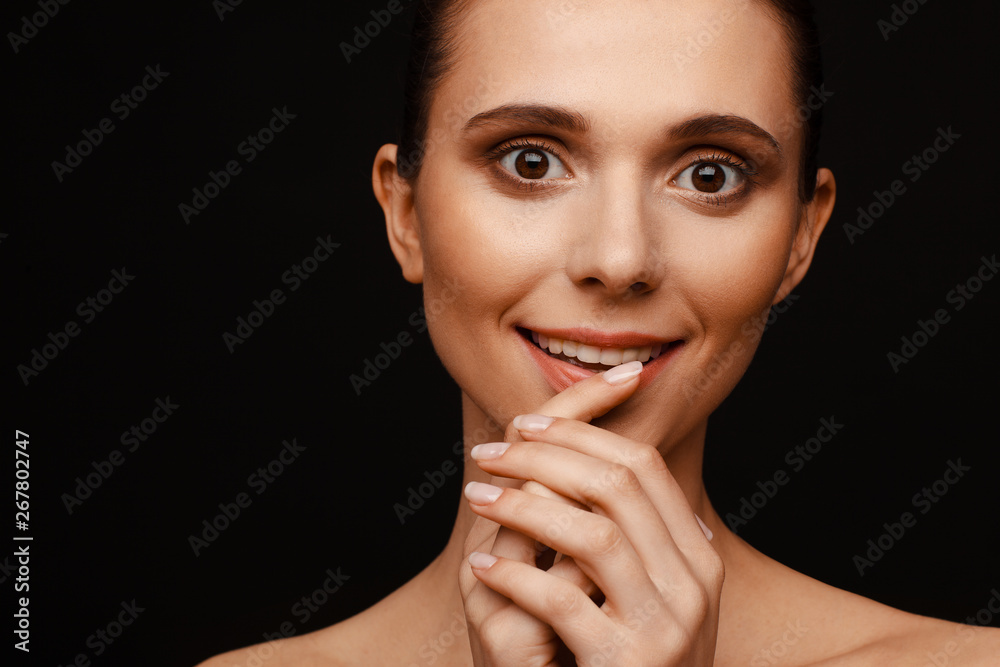 Portrait of a beautiful woman with collected hair and bare shoulders on a black background Portrait of a beautiful woman with collected hair and bare shoulders on a black background