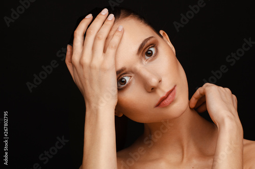 Portrait of a beautiful woman with collected hair and bare shoulders on a black background