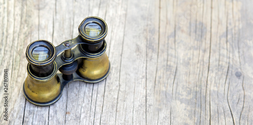 Search concept, old binoculars on wooden background, web banner with copy space
