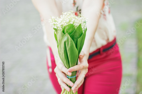 woman holding a bouquet of lily of the valley. Spring mood. Free space for text. Walk in the summer park.