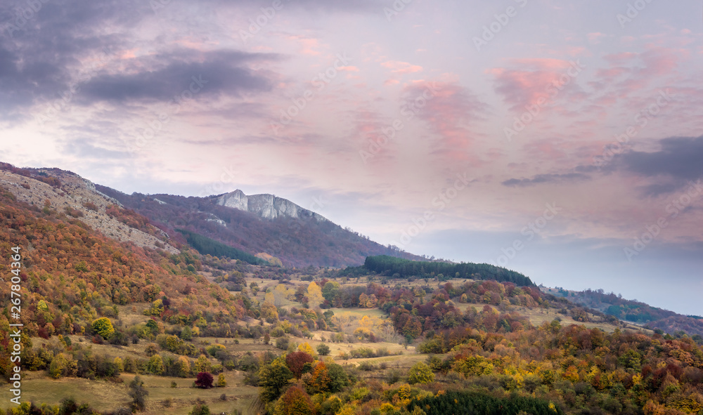 Panorama of stunning autumn colors of mountain forest and beautiful sunset sky