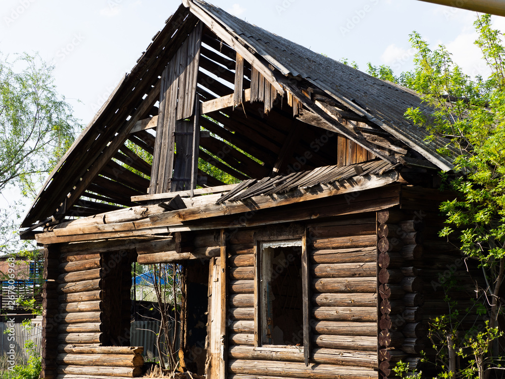 Wooden ruined house. Old house without windows and doors, broken roof.