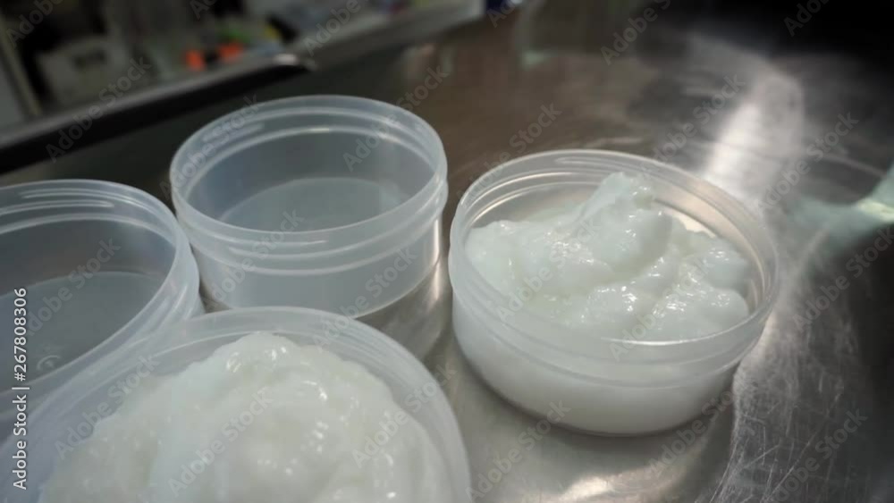 Closeup of several plastic jars with body cream on the metal table in cosmetics laboratory Closeup of several plastic jars with body cream on the metal table in cosmetics laboratory