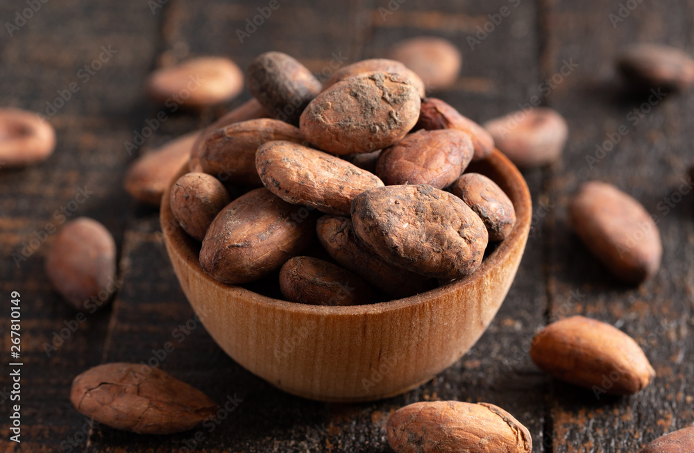 Obraz premium Bowl of Cocoa Beans on a Dark Wooden Table