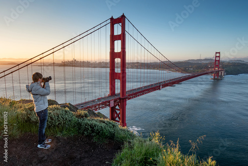 Asian man photographer and tourist enjoy taking photo of Golden Gate Bridge during sunrise, Iconic bridge and famous landmark of San Francisco, California, USA. Travel photography concept © zephyr_p