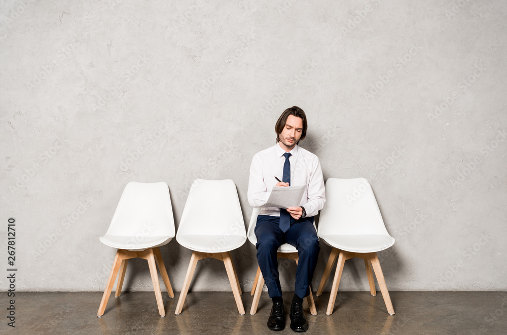 Fototapeta premium handsome man sitting on chair while waiting job interview in office
