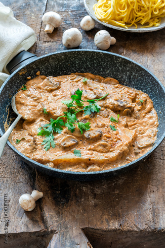 Pork chops in creamy cajun sauce with button mushrooms and parsley in a skillet