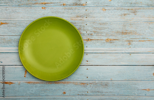Empty green ceramic dish plate, on wooden white blue background. Top view with copy space.