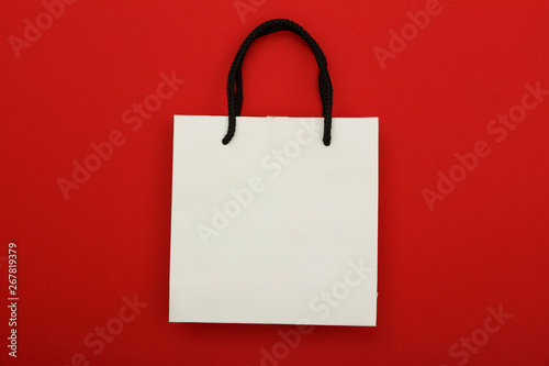White paper bag package on red background. Place for text. Mock up concept for gift wrapping.