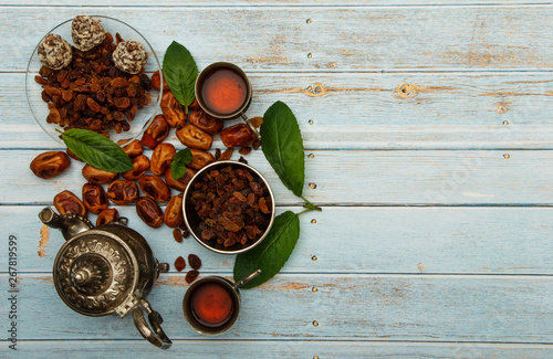 Traditional Arabic, Turkish Ramadan tea with dry dates and raisins on a wooden white table. A cup of tea on a white table.Turkish fresh tea with dates. Ramadan kareem. Ramadan background. 