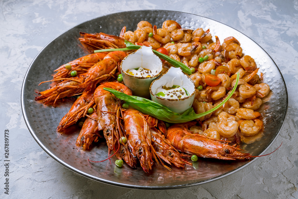 some langoustines on a plate on grey concrete and grilled shrimps some langoustines on a plate on grey concrete and grilled shrimps