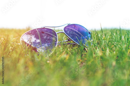 Soft focus, sunglasses on the green grass, summer mood.