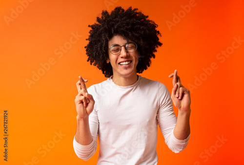 Cheerful black guy crossing fingers for luck photo
