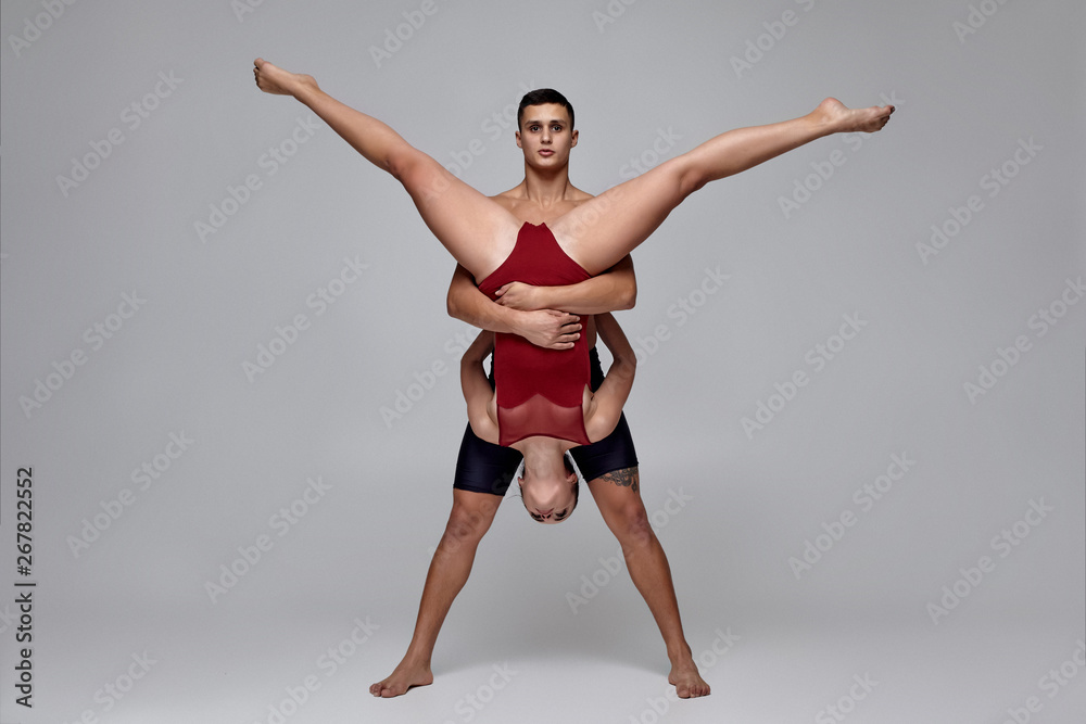The couple of an athletic modern ballet dancers are posing against a gray studio background. The couple of an athletic modern ballet dancers are posing against a gray studio background.