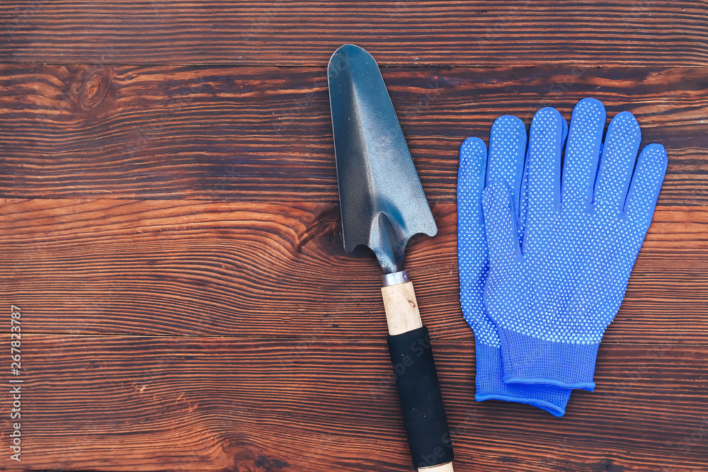 garden tools on a wooden background gloves and shovel