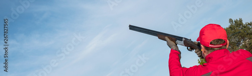 man shooting trap or skeet with a shotgun,  clay pigeon shooting on the sky background, panoramic banner , Images with Copy Space photo