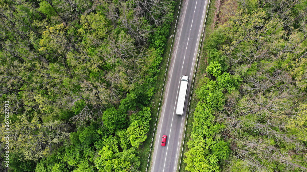 Cargo delivery. Wagon truck and red car driving on the highway, aerial. Transport logistics background top view. Cargo delivery. Wagon truck and red car driving on the highway, aerial. Transport logistics background top view.