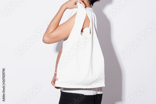 Girl is holding bag canvas fabric for mockup blank template isolated on gray background. global warming concept.