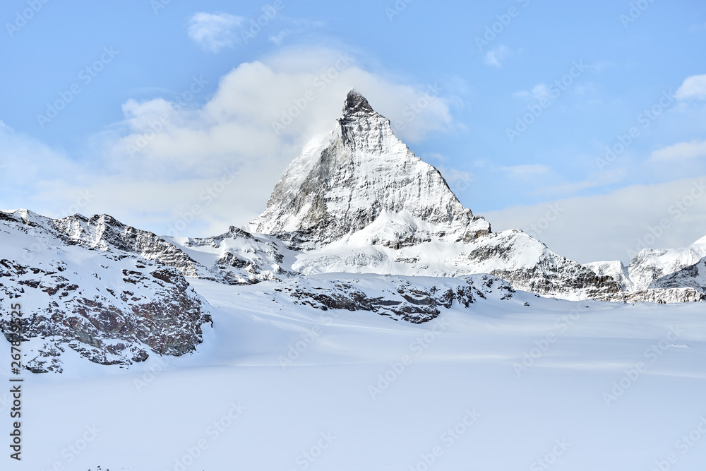 beautiful view of the Matterhorn from the ski slopes in the winter on a beautiful clear day. Blue sky and small clouds beautifully highlight the beauty of the legendary mountain.    