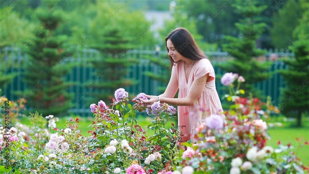 Young girl in a flower garden among beautiful roses. Smell of roses Young girl in a flower garden among beautiful roses. Smell of roses