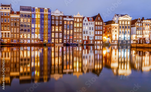 Canvas Print Scenic night view of traditional colourful old houses and boats with reflection on canal Damrak in the old city of Amsterdam, Netherlands