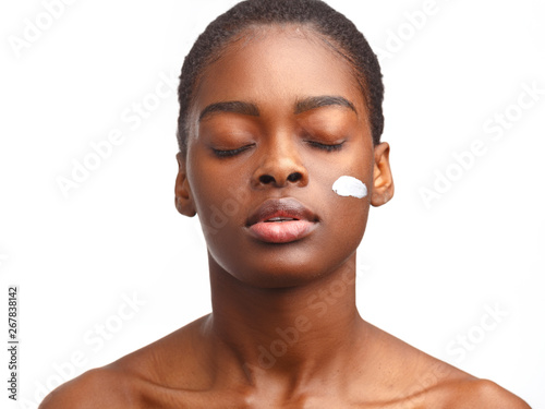 Young attractive African girl with a smear of cream on her face. Skin care concept.