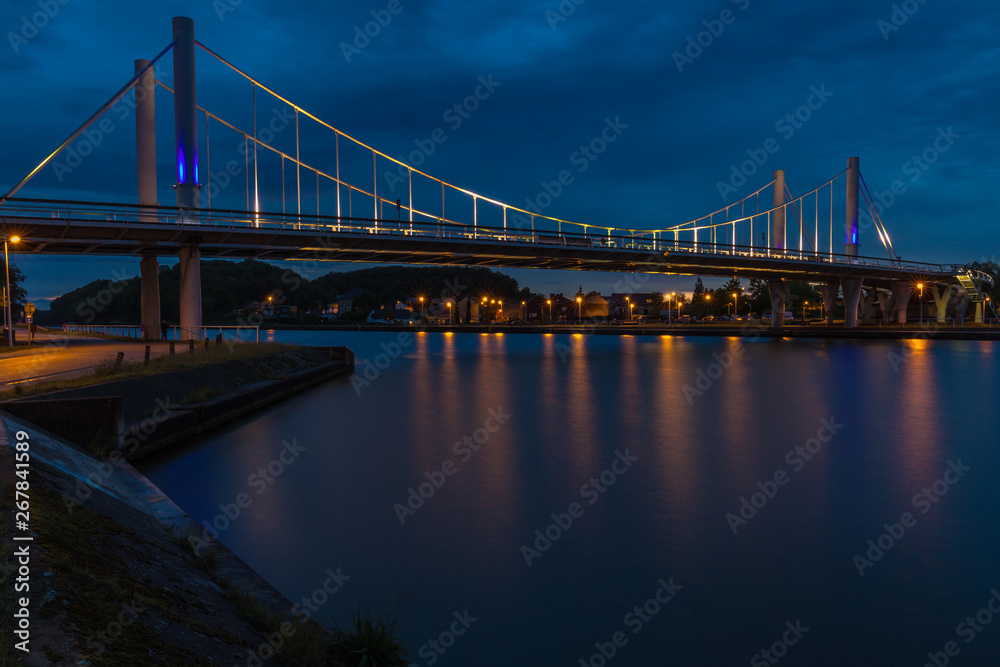 The first suspension bridge in Belgium located in Kanne with a span of 120 against a dramatic evening sky during twilight