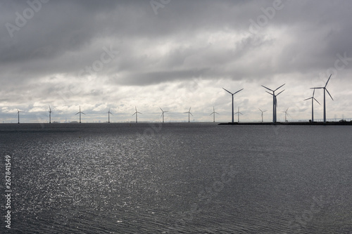 wind turbines standing tall and proud across the horizon. Grey overcast weather that makes a dramatic grey scale picture of green energy photo