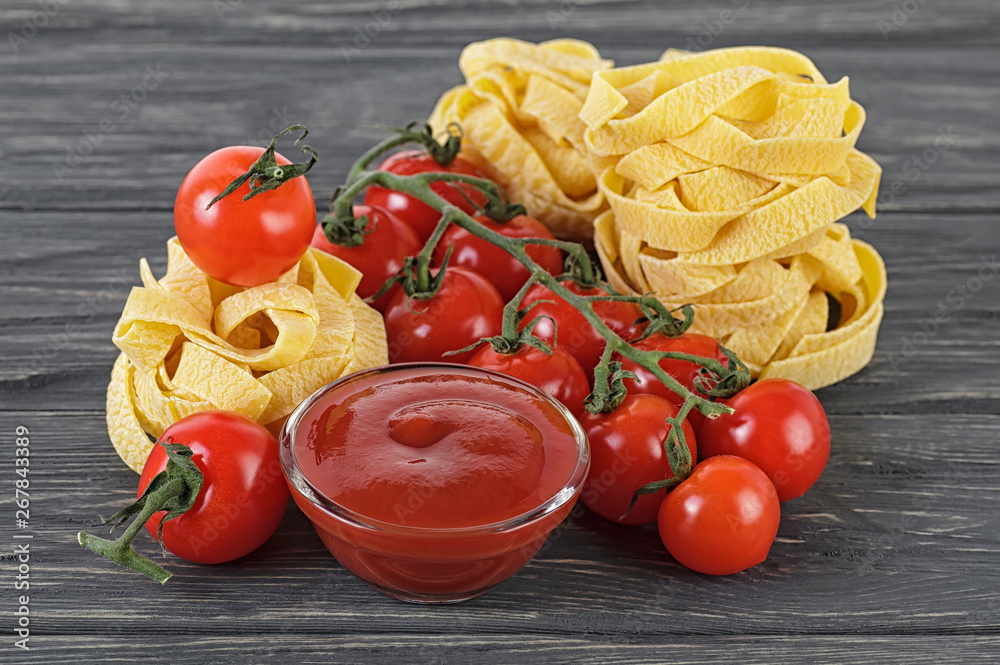 Bowl of tomato sauce, cherry tomatoes and italian pasta on wooden background Bowl of tomato sauce, cherry tomatoes and italian pasta on wooden background