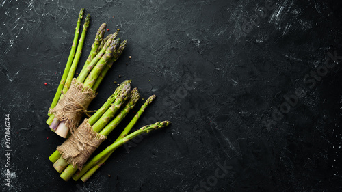 Fresh green asparagus on a black stone background. Top view. Free space for your text.
