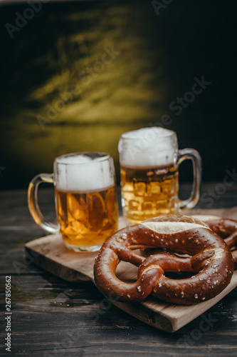 pretzels and draft beer on rustic cutting board against dark background